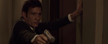 Movie still from “Anon” (2018), directed by Andrew Niccol – A man in a suit and tie holding a gun; Close Up shot, Low angle