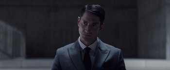 Movie still from “Anon” (2018), directed by Andrew Niccol – A person wearing a suit and tie; Close Up shot, Over the shoulder angle