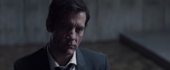 Movie still from “Anon” (2018), directed by Andrew Niccol – A person wearing a suit and tie; Close Up shot, Over the shoulder angle