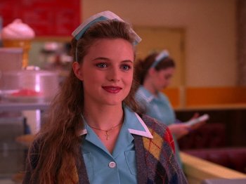 Movie still from “Twin Peaks” (1990), created by David Lynch – A woman in a blue shirt is smiling for the camera; Close Up shot, High angle