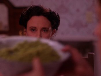 Movie still from “Twin Peaks” (1990), created by David Lynch – A woman holding a paper plate with food in front of her face; Close Up shot, Over the shoulder angle