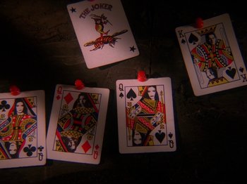 Movie still from “Twin Peaks” (1990), created by David Lynch – A group of playing cards sitting on top of a wooden table; Extreme Close Up shot, Overhead angle