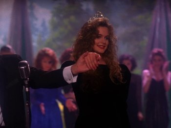 Movie still from “Twin Peaks” (1990), created by David Lynch – A woman in a black dress and a tiara is pointing to the camera; Medium shot, Over the shoulder angle