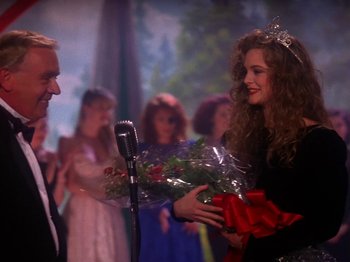 Movie still from “Twin Peaks” (1990), created by David Lynch – A woman holding a bouquet of flowers and a microphone; Medium shot, Over the shoulder angle