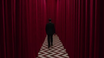 Movie still from “Twin Peaks” (2017), directed by David Lynch – A man in a black and white suit walking down a hall way with red drapes; Wide shot, Low angle