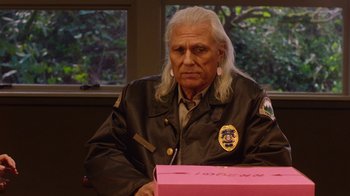 Movie still from “Twin Peaks” (2017), directed by David Lynch – An older man with long white hair wearing a police uniform; Close Up shot, Over the shoulder angle