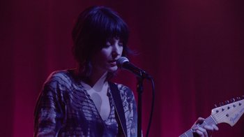 Movie still from “Twin Peaks” (2017), directed by David Lynch – A woman is singing into a microphone on a stage; Medium shot, Low angle