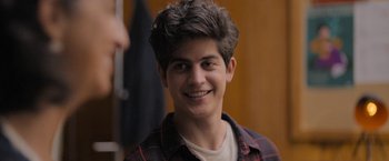 Movie still from “Anonymously Yours” (2021), directed by Maria Torres – A young man smiling for the camera in front of a mirror; Close Up shot, Over the shoulder angle