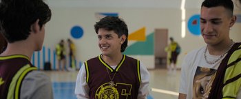 Movie still from “Anonymously Yours” (2021), directed by Maria Torres – A young man in a maroon and yellow shirt; Medium shot, Over the shoulder angle