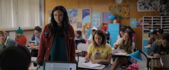 Movie still from “Anonymously Yours” (2021), directed by Maria Torres – Two girls are sitting at a table in a classroom; Medium shot, Over the shoulder angle