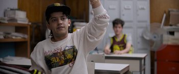 Movie still from “Anonymously Yours” (2021), directed by Maria Torres – A young man raises his hand in front of another young man; Medium shot, Over the shoulder angle