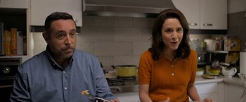 Movie still from “Anonymously Yours” (2021), directed by Maria Torres – A man and a woman sitting at a table in a kitchen; Medium shot, Over the shoulder angle