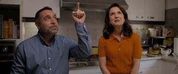 Movie still from “Anonymously Yours” (2021), directed by Maria Torres – A man and a woman standing next to each other in a kitchen; Medium shot, Low angle