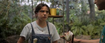 Movie still from “Anonymously Yours” (2021), directed by Maria Torres – A woman holding a piece of paper in her hand; Medium shot, Over the shoulder angle