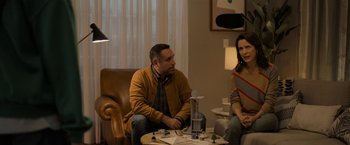 Movie still from “Anonymously Yours” (2021), directed by Maria Torres – A man and a woman are sitting in a living room; Medium shot, Over the shoulder angle