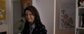Movie still from “Anonymously Yours” (2021), directed by Maria Torres – A woman smiling for the camera while wearing a jacket; Medium shot, Over the shoulder angle
