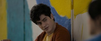 Movie still from “Anonymously Yours” (2021), directed by Maria Torres – A young man in a yellow and brown shirt; Close Up shot, Over the shoulder angle