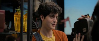 Movie still from “Anonymously Yours” (2021), directed by Maria Torres – A young man in a yellow t - shirt and orange sweater; Close Up shot, Over the shoulder angle
