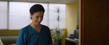 Movie still from “Anonymously Yours” (2021), directed by Maria Torres – A woman in a blue shirt smiling for the camera; Medium shot, Over the shoulder angle