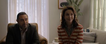 Movie still from “Anonymously Yours” (2021), directed by Maria Torres – A woman sitting in front of a man in a chair; Medium shot, Over the shoulder angle