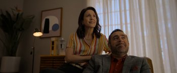 Movie still from “Anonymously Yours” (2021), directed by Maria Torres – A man and a woman sitting in a living room; Medium shot, Low angle