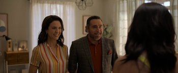 Movie still from “Anonymously Yours” (2021), directed by Maria Torres – A man and a woman standing next to each other in a room; Medium shot, Over the shoulder angle