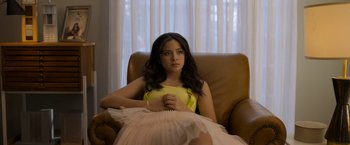 Movie still from “Anonymously Yours” (2021), directed by Maria Torres – A woman sitting in a chair in front of a window; Medium shot, High angle