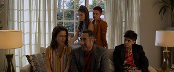 Movie still from “Anonymously Yours” (2021), directed by Maria Torres – A group of people sitting on top of a white couch; Medium shot, Over the shoulder angle