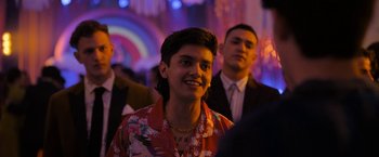 Movie still from “Anonymously Yours” (2021), directed by Maria Torres – A man in a hawaiian shirt is smiling for the camera; Medium shot, Over the shoulder angle