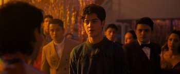 Movie still from “Anonymously Yours” (2021), directed by Maria Torres – A young man standing in front of other men; Medium shot, Over the shoulder angle