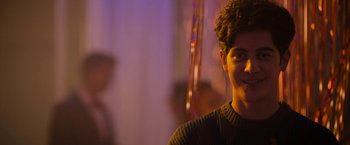 Movie still from “Anonymously Yours” (2021), directed by Maria Torres – A young man is smiling for the camera; Close Up shot, Over the shoulder angle