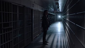 Movie still from “Twin Peaks” (2017), directed by David Lynch – A man standing in a dark room in front of a jail cell; Wide shot, Low angle