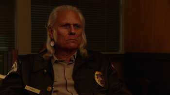Movie still from “Twin Peaks” (2017), directed by David Lynch – An older man with long white hair wearing a police uniform; Close Up shot, Over the shoulder angle