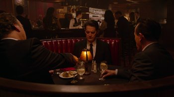 Movie still from “Twin Peaks” (2017), directed by David Lynch – A man sitting at a table in front of two other people; Medium shot, High angle