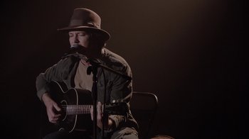 Movie still from “Twin Peaks” (2017), directed by David Lynch – A man with a hat playing a guitar; Medium shot, Low angle