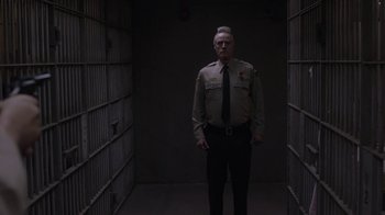 Movie still from “Twin Peaks” (2017), directed by David Lynch – A police officer standing in a jail cell with his hands in his pockets; Medium shot, Low angle