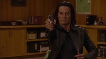 Movie still from “Twin Peaks” (2017), directed by David Lynch – A man holding a gun in a room; Medium shot, Over the shoulder angle