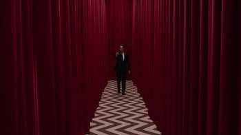 Movie still from “Twin Peaks” (2017), directed by David Lynch – A man in a suit and tie standing in front of a red curtain; Extreme Wide shot, Low angle