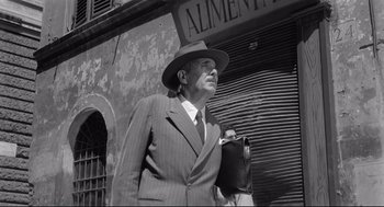 Movie still from “Two Women” (1960), directed by Vittorio De Sica – An older man in a suit and hat is holding a bag; Medium shot, Low angle