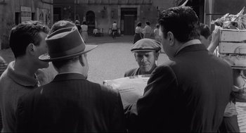 Movie still from “Two Women” (1960), directed by Vittorio De Sica – A group of men standing next to each other on a street; Medium shot, Over the shoulder angle