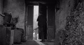 Movie still from “Two Women” (1960), directed by Vittorio De Sica – An old man is standing at the door of a house; Wide shot, Low angle