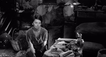 Movie still from “Two Women” (1960), directed by Vittorio De Sica – A black and white photo of a woman sitting at a table; Medium shot, High angle