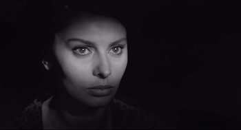 Movie still from “Two Women” (1960), directed by Vittorio De Sica – A black and white photo of a woman's face in the dark; Close Up shot, Over the shoulder angle