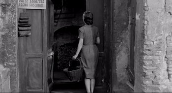 Movie still from “Two Women” (1960), directed by Vittorio De Sica – A black and white photo of a woman carrying a basket; Medium shot, Low angle
