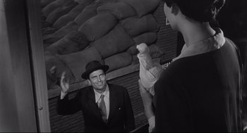 Movie still from “Two Women” (1960), directed by Vittorio De Sica – A man in a suit and a hat standing in front of two other men; Medium shot, Over the shoulder angle