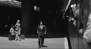 Movie still from “Two Women” (1960), directed by Vittorio De Sica – A black and white photo of a man in a suit and tie; Wide shot, Low angle