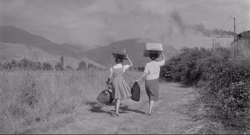 Movie still from “Two Women” (1960), directed by Vittorio De Sica – Two women carrying suitcases on a dirt road; Wide shot, Low angle