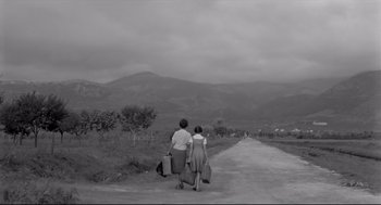 Movie still from “Two Women” (1960), directed by Vittorio De Sica – Two people walking down a dirt road carrying luggage; Extreme Wide shot, Low angle
