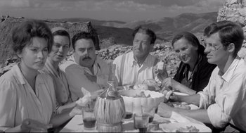 Movie still from “Two Women” (1960), directed by Vittorio De Sica – A black and white photo of a group of people sitting at a table; Medium shot, High angle