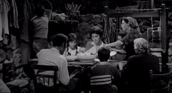 Movie still from “Two Women” (1960), directed by Vittorio De Sica – A group of people sitting around a table; Wide shot, High angle